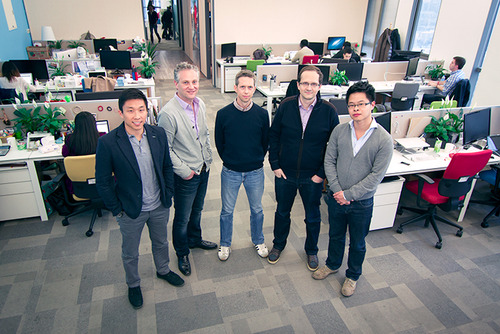 Five people stand in a semi-circle in an office setting