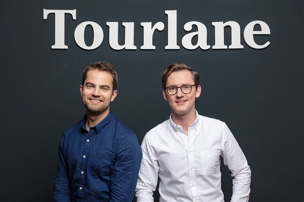 Two men posing beneath a Tourlane logo